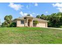 Attractive one-story home with a tidy yard and two-car garage under a bright blue sky at 1693 Jagust Rd, North Port, FL 34288