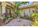 A cozy courtyard features a patterned brick patio surrounded by lush tropical landscaping and a bird bath at 17188 Cape Horn Blvd, Punta Gorda, FL 33955