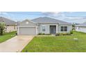 Well-maintained one-story home with a lush green lawn, gray exterior, and a two-car garage at 17200 Gulfspray Cir, Port Charlotte, FL 33948