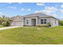 Well-maintained one-story home with a lush green lawn, gray exterior, and a two-car garage at 17200 Gulfspray Cir, Port Charlotte, FL 33948