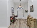 Bright foyer with stylish decor, featuring wood floors, decorative tables and arch window above door at 24504 Buckingham Way, Punta Gorda, FL 33980