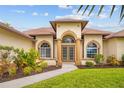 Charming home featuring a welcoming front entrance with arched windows and lush tropical landscaping at 37 Marker Rd, Rotonda West, FL 33947