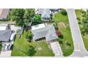 Aerial shot of a cozy home with a well-manicured lawn, mature trees, and a paved driveway at 475 Whippoorwill Dr, Venice, FL 34293
