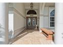 Inviting front porch with tiled flooring, decorative columns, and a cozy bench at 5048 San Massimo Dr, Punta Gorda, FL 33950