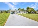 Single-story home features a long driveway, carport, well-maintained lawn, and green landscaping at 769 Crestview Nw Cir, Port Charlotte, FL 33948