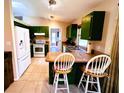 A kitchen features green cabinets, beige countertops, tile flooring, and stainless steel appliances at 15090 Rebecca Ave, Port Charlotte, FL 33953