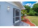 Close-up of the home's exterior with decorative landscaping, freshly painted and screened entry at 732 Haleybury St, Port Charlotte, FL 33948