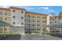 Low angle view of a multi-story condo with white facade, red tiled roof, balconies, and covered parking at 915 Beach Rd # 215, Siesta Key, FL 34242