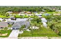 Waterfront home surrounded by lush landscaping, canal access, and mature palm trees at 18483 Hottelet Cir, Port Charlotte, FL 33948