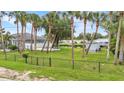 Fenced backyard with lush greenery, tall palm trees, canal access, and ample space at 18483 Hottelet Cir, Port Charlotte, FL 33948