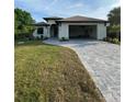 Single-story home with attached garage and gray paver driveway at 124 Hercules Dr, Rotonda West, FL 33947