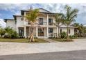Stunning two-story home with a spacious front porch, wooden details, complemented by verdant palm trees and a stone driveway at 10009 Gasparilla Pass Blvd, Boca Grande, FL 33921