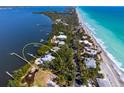 Breathtaking aerial shot of a beachfront property with lush surroundings, a private dock, and crystal-clear turquoise waters at 6895 Manasota Key Rd, Englewood, FL 34223