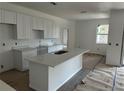 Spacious kitchen featuring white cabinets, quartz countertops, and a large island, still under construction at 5462 Gagnon Ter, North Port, FL 34291