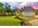House exterior featuring a landscaped lawn, paver driveway, and two-car garage at 7192 N Paragon Rd, North Port, FL 34291