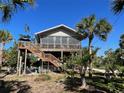 Stilted beach home with wrap-around porch and tropical landscaping at 8934 Gulf St, Placida, FL 33946