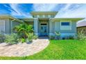 Front view of a home with light gray exterior, teal door, and landscaping at 777 Boundary Blvd, Rotonda West, FL 33947