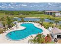 Aerial view of the community pool, surrounded by lounge chairs, landscaping, and a lake at 175 Kings Hwy # 1014, Punta Gorda, FL 33983