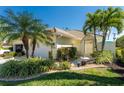 Front view of a house with a tan facade and tropical landscaping at 28260 Pablo Picasso Dr, Englewood, FL 34223