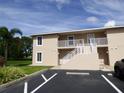 Two-story building with light beige exterior, stairs, and parking at 9600 Fiddlers Green Cir # 212, Rotonda West, FL 33947