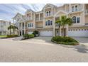 Three-story townhouses with white garage doors and lush landscaping at 10380 Longshore Rd # 77, Placida, FL 33946