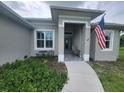 Front porch of a gray house with American flag and landscaping at 48 Long Meadow Ln, Rotonda West, FL 33947
