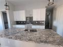 Modern kitchen with white cabinets, granite countertops, and dark tile backsplash at 2170 Doolittle Ln, Port Charlotte, FL 33953