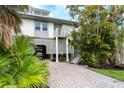 Elevated home with a large, paved driveway, lush landscaping, and golf cart at 7104 Palm Island Dr # Le38, Placida, FL 33946
