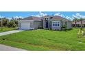 Single-Gathering home with a two-car garage and a manicured lawn at 8111 Arlewood Cir, Port Charlotte, FL 33981