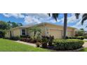 Tan house exterior with double garage, landscaping, and a walkway at 13524 Abercrombie Dr, Englewood, FL 34223