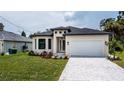 Modern one-story house with a two-car garage, landscaping and paver driveway at 205 Cougar Way, Rotonda West, FL 33947