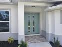 Inviting front entrance featuring a double door and tiled entryway framed by decorative plants and white trim at 261 Broadmoor Ln, Rotonda West, FL 33947