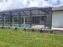 Backyard pool area enclosed with screen, featuring a concrete patio and minimal landscaping at 261 Broadmoor Ln, Rotonda West, FL 33947