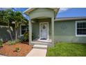 Green house exterior with a covered porch, landscaping, and a walkway at 10236 Willmington Blvd, Englewood, FL 34224