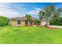 Single-Gathering house with tan exterior, palm trees, and a landscaped yard at 14143 Saul Ln, Port Charlotte, FL 33981