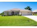 House exterior featuring a two-car garage and well-manicured lawn at 283 Long Meadow Ln, Rotonda West, FL 33947