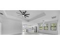 Bright living space boasts modern fan, tray ceiling, and large windows, with access to the kitchen at 9262 Genesee St, Port Charlotte, FL 33981