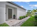 Front entryway with a dark brown door, landscaping, and a brick paver walkway at 1352 Sunset Preserve Way, Port Charlotte, FL 33953
