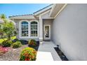 Inviting front entrance with beautifully landscaped garden beds and large windows, creating a warm and welcoming feel at 3359 Osprey Ln, Port Charlotte, FL 33953