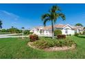 Landscaped yard with lush green grass and palm trees surrounds home at 8216 Parkside Dr, Englewood, FL 34224