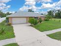 Ranch-style home featuring a gray roof and a two-car garage at 7506 Spinnaker Blvd, Englewood, FL 34224