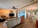 Open-concept living room with a ceiling fan, hardwood floors, and a cozy dining area at 5704 Holiday Park Blvd, North Port, FL 34287