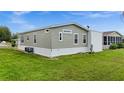 Side view of tan mobile home with grassy yard at 9085 Pinehaven Way, Englewood, FL 34224