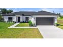Charming single-story home showcasing a modern design with a gray roof, lawn, and a gray two-car garage at 220 Mark Twain Ln, Rotonda West, FL 33947