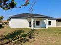 The rear exterior features an open lawn, small patio and new tree with views of nearby home at 235 Albatross Rd, Rotonda West, FL 33947