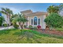 Tan one-story house with a red door, two-car garage, and lush landscaping at 2803 Sawgrass Ct, Port Charlotte, FL 33953