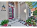 Front door entry with red door, landscaping and brick walkway at 2803 Sawgrass Ct, Port Charlotte, FL 33953
