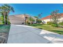 Tan one-story house with a red door, two-car garage, and lush landscaping at 2803 Sawgrass Ct, Port Charlotte, FL 33953