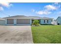 Light blue house with a three-car garage and a well-maintained lawn at 153 Broadmoor Ln, Rotonda West, FL 33947