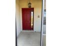 Inviting red front door entryway with light-colored walls and concrete flooring at 2704 Suncoast Lakes Blvd, Punta Gorda, FL 33980